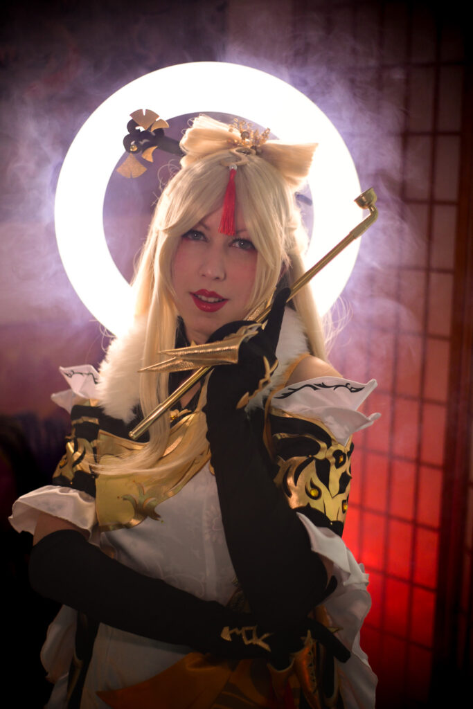 Ningguang aus dem Spiel "Genshin Impact" steht vor einem Ringlicht, umhüllt von Nebel. Im Hintergrund ist ein rot angeleuchteter Paravent.