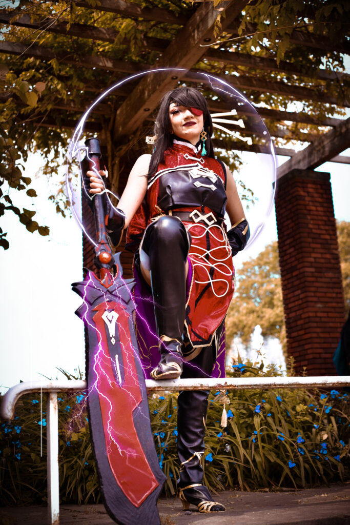 Der Charakter Beidou, aus dem Spiel Genshin Impact, steht vor ein paar Steinsäulen mit überwachsenem Dach aus Ranken und Blättern. Sie stützt sich auf ihrem großen Sschwert und ist von für sie typischen lila Blitzen umhüllt.