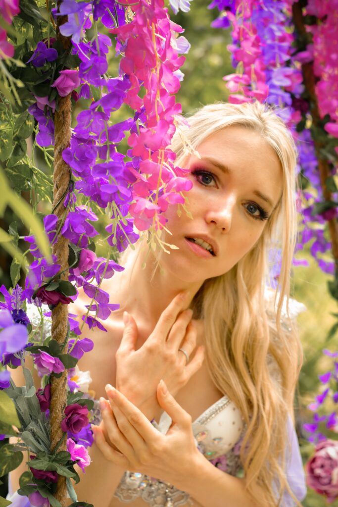 Fantasy-Portrait einer Frau umringt von einem Meer aus lila und rosanen Blüten.