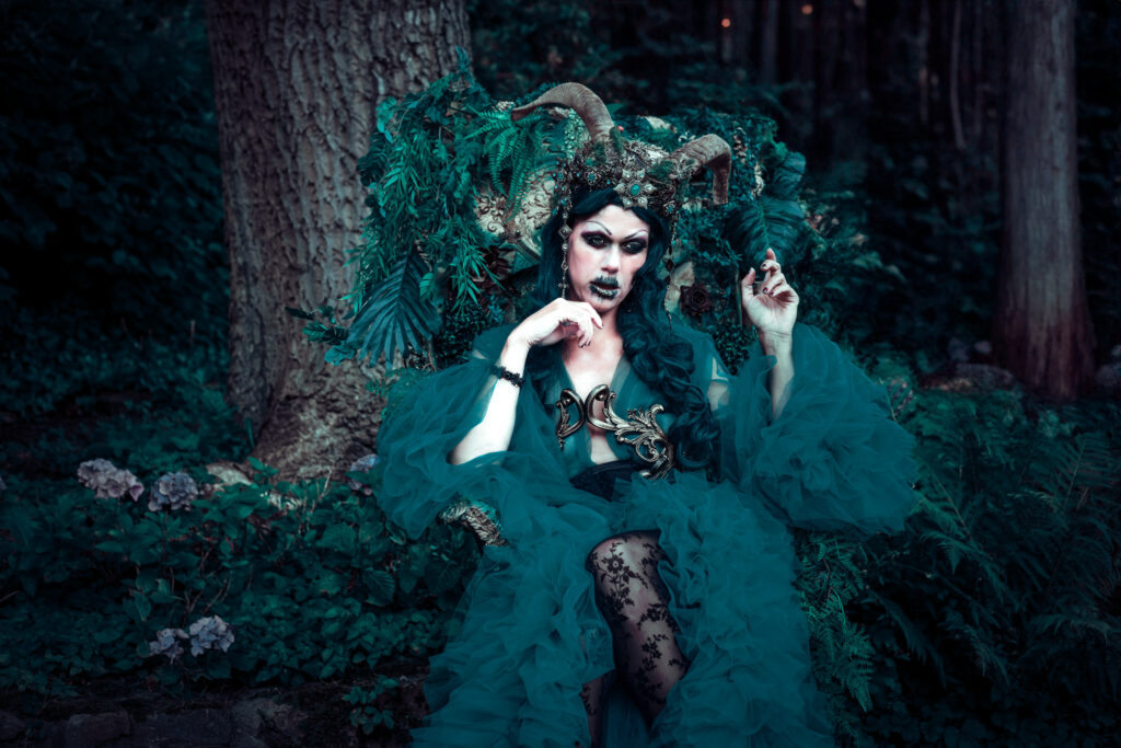 Eine Dschungelkönigin in ihrem Wald wartet auf ihrem Thron. Ihre großen Hörner und ihr dunkelgrünes Make-Up lassen sie furchteinflößend wirken.