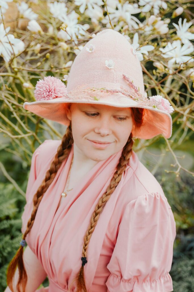 Frau mit rosa Kleid und Blumenhut beim Fantasy Hexen Fotoshooting in Köln, umgeben von Blüten.